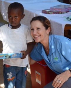 Woman kneeling in blue shirt and smiling. Young boy in white t-shirt standing next.