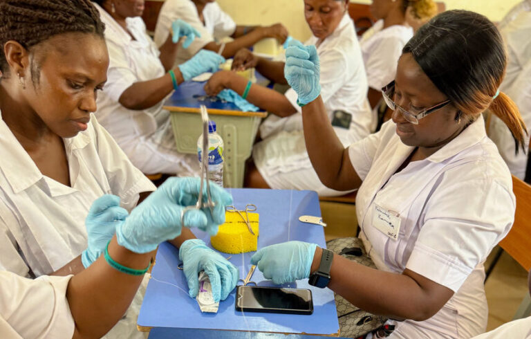 Nurses around a table practicing sutures