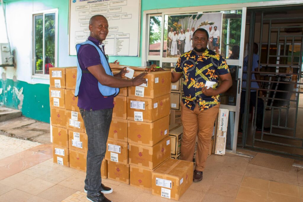 Two men standing around boxes of medicines