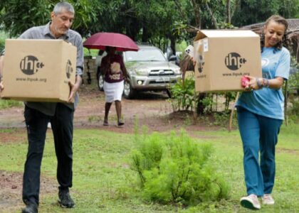 Two people carrying boxes with IHP label