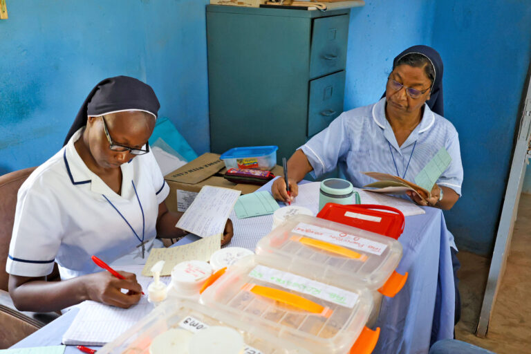 Two religious sisters at a table preparing medicines