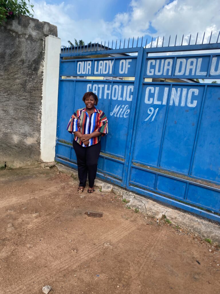 Woman standing in front of a gate with a health care facility name written on it