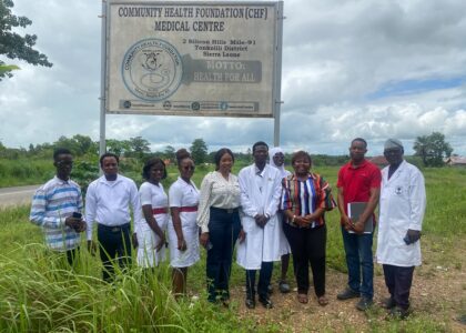A group of people standing outside in front of a sign